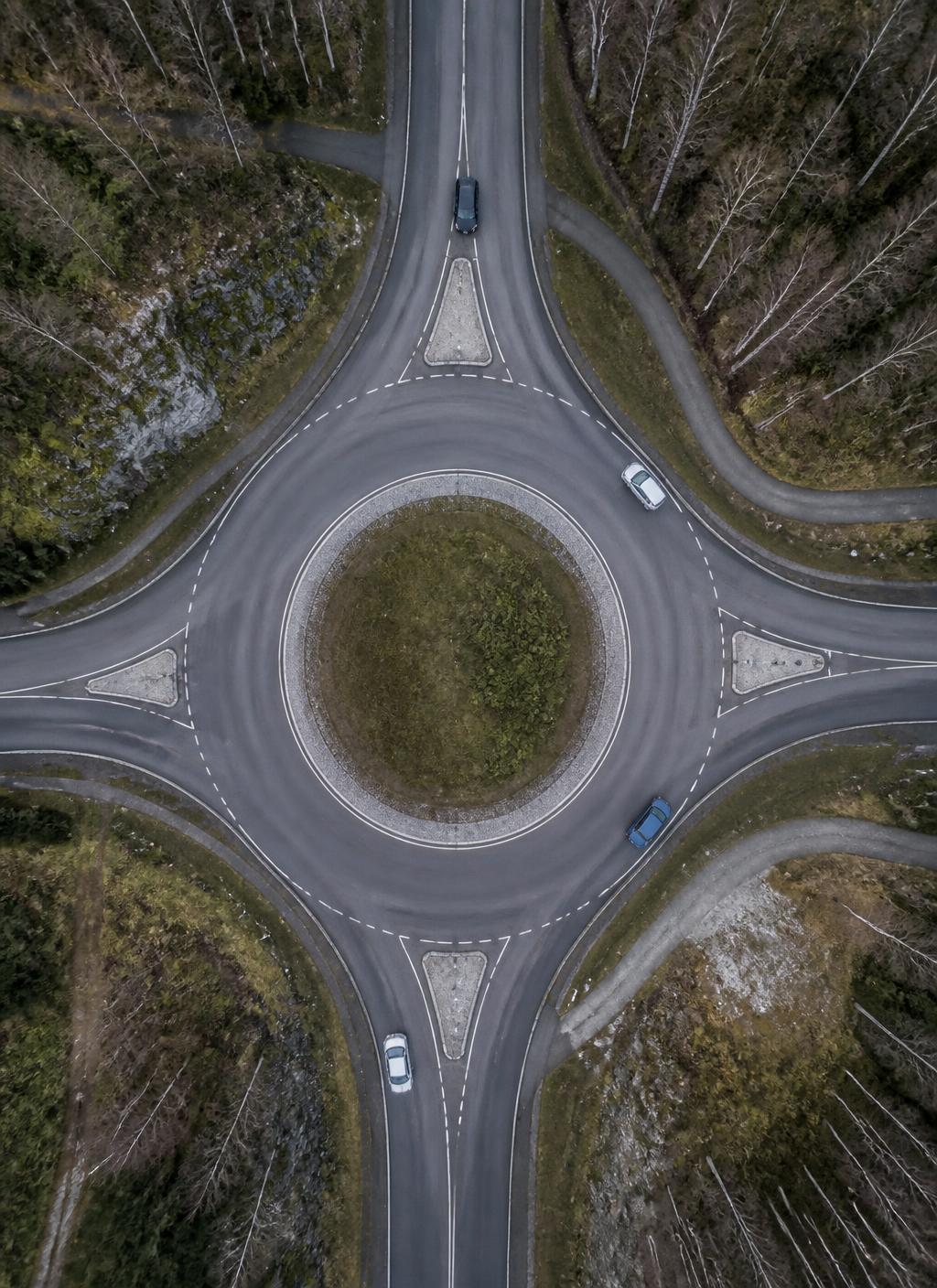 Svensk rondell fotograferad rakt uppifrån med drönare, med vägmarkeringar och grönt mittparti